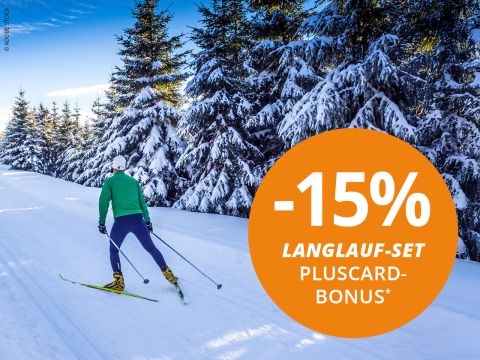 Zwei Personen laufen auf einer verschneiten Piste mit Bergen im Hintergrund Ski. Beide tragen Winterkleidung und Sonnenbrillen. Ein orangefarbener Kreis im Bild zeigt „-15% Langlauf-Set Pluscard Bonus“.