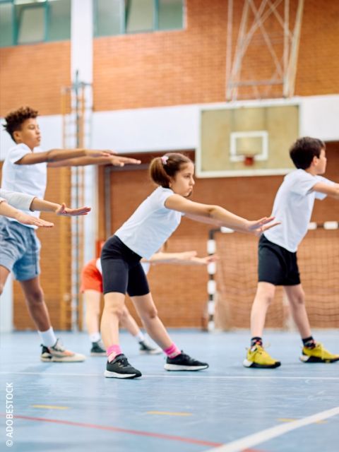 Nahaufnahme eines Kindes, das graue Turnschuhe mit roten Nike-Swooshes trägt und auf einer blauen Fläche steht. Der Hintergrund ist mit weichen, bunten Formen verschwommen.