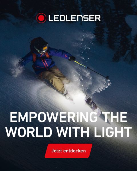 Ein Skifahrer mit Stirnlampe fährt nachts bergab, beleuchtet von hellem Licht, mit dem Text "LEDLENSER Empowering the world with light" und "Jetzt entdecken.